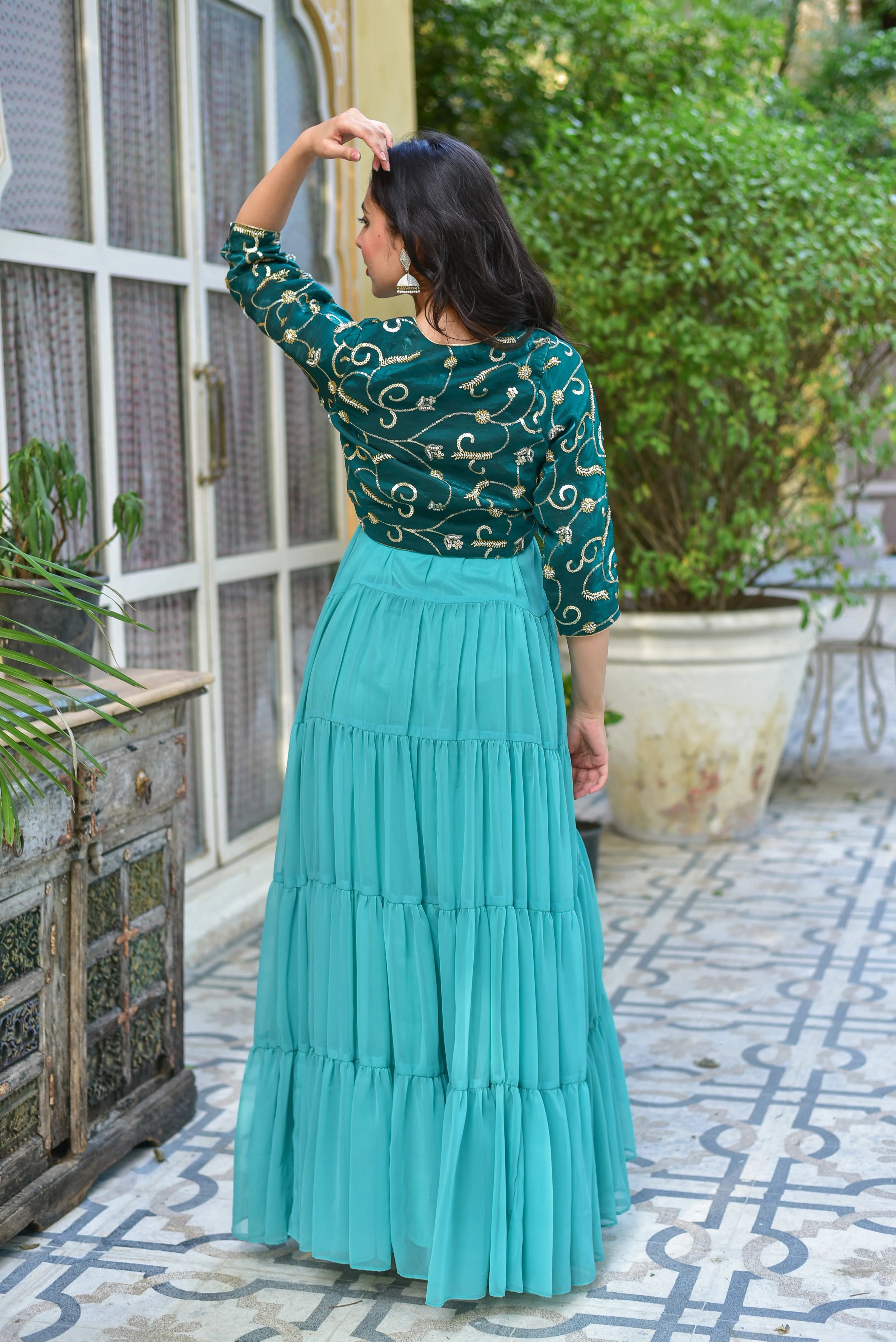 The green stunning tired dress with jacket is a masterpiece of elegance and sophistication, featuring a contemporary silhouette that exudes modernity while maintaining traditional craftsmanship. The flowing georgette fabric of the dress is adorned with graceful tiers that create beautiful movement with every step, making it perfect for any occasion. The jacket adds a touch of luxury with its intricate details, elevating the overall look to new heights.