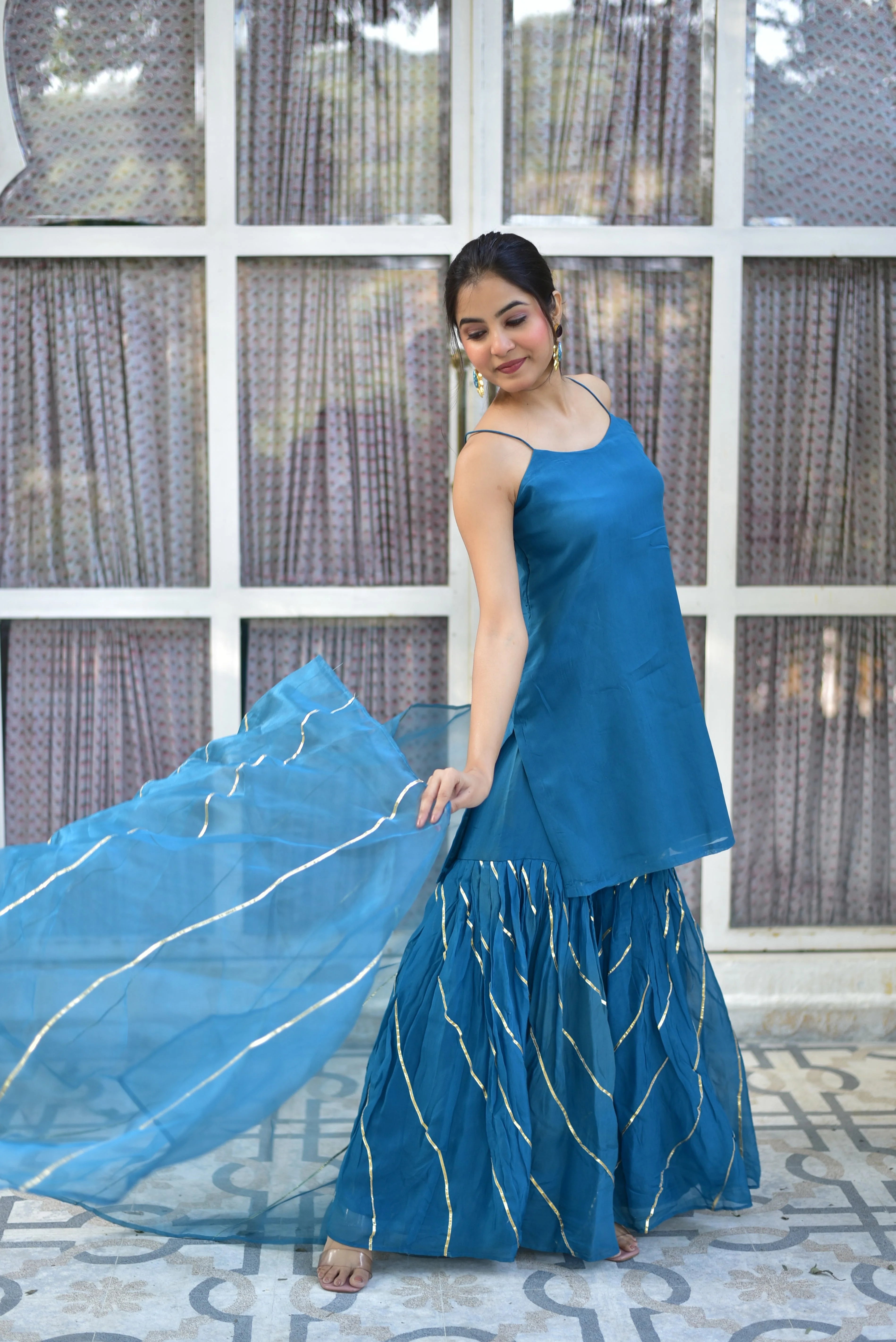 The Teal Blue Kurta Sharara Set is a stunning ensemble that seamlessly blends traditional elegance with modern sophistication. Crafted from high-quality fabrics, this set features a flowing kurta with intricate gold accents and a matching sharara adorned with delicate embroidery. The vibrant teal blue hue adds a touch of freshness to the overall design, making it perfect for any occasion.