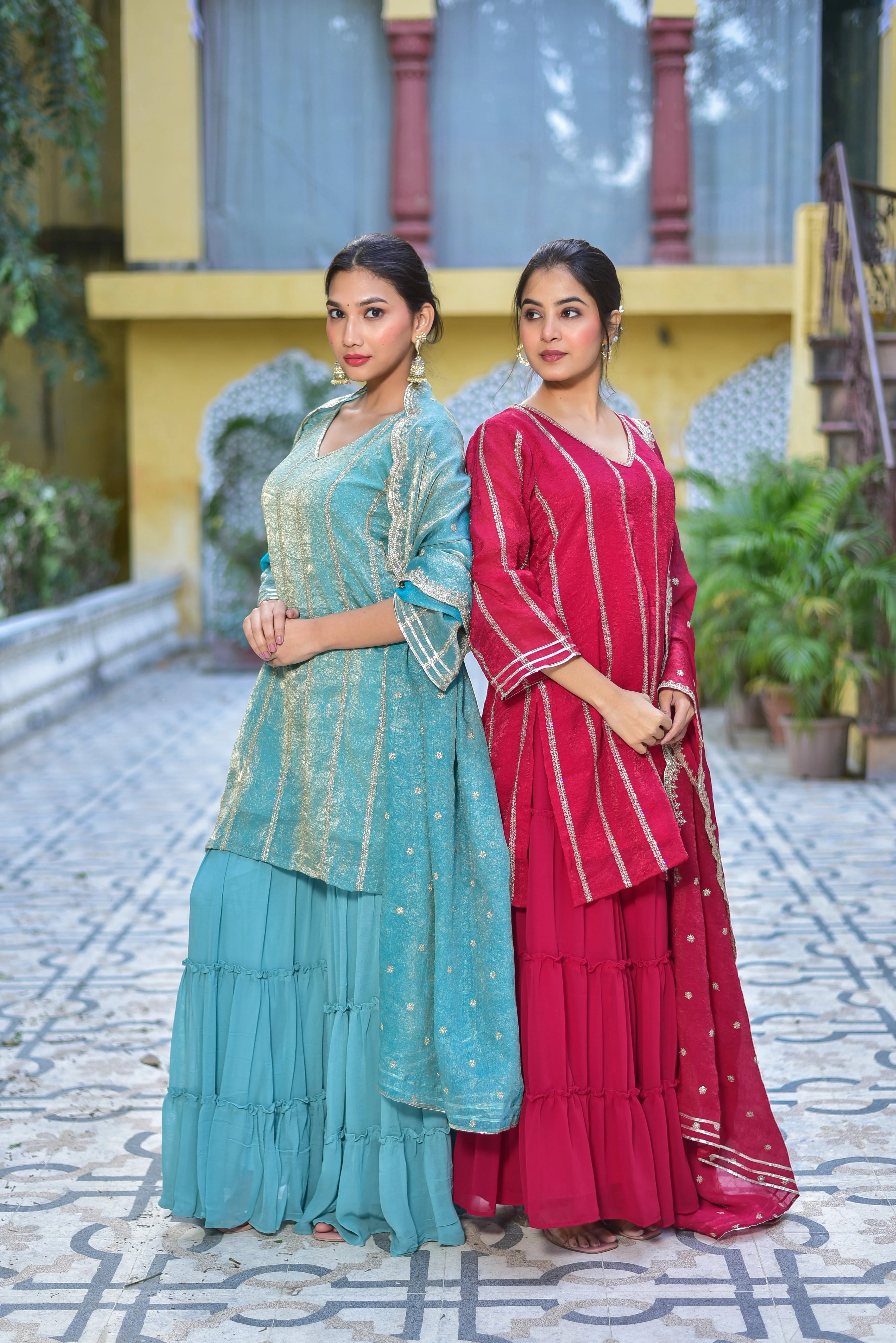 This image showcases a stunning Magenta Heavy Sharara Set, exuding elegance and sophistication. The set features a heavy, intricately designed kurta with a V-neckline and three-quarter sleeves, crafted from rich magenta fabric adorned with gold accents. The sharara pants are wide and flowy, complemented by a matching dupatta with a subtle gold pattern. The set is perfect for special occasions, offering a regal and fashionable look that is sure to turn heads.