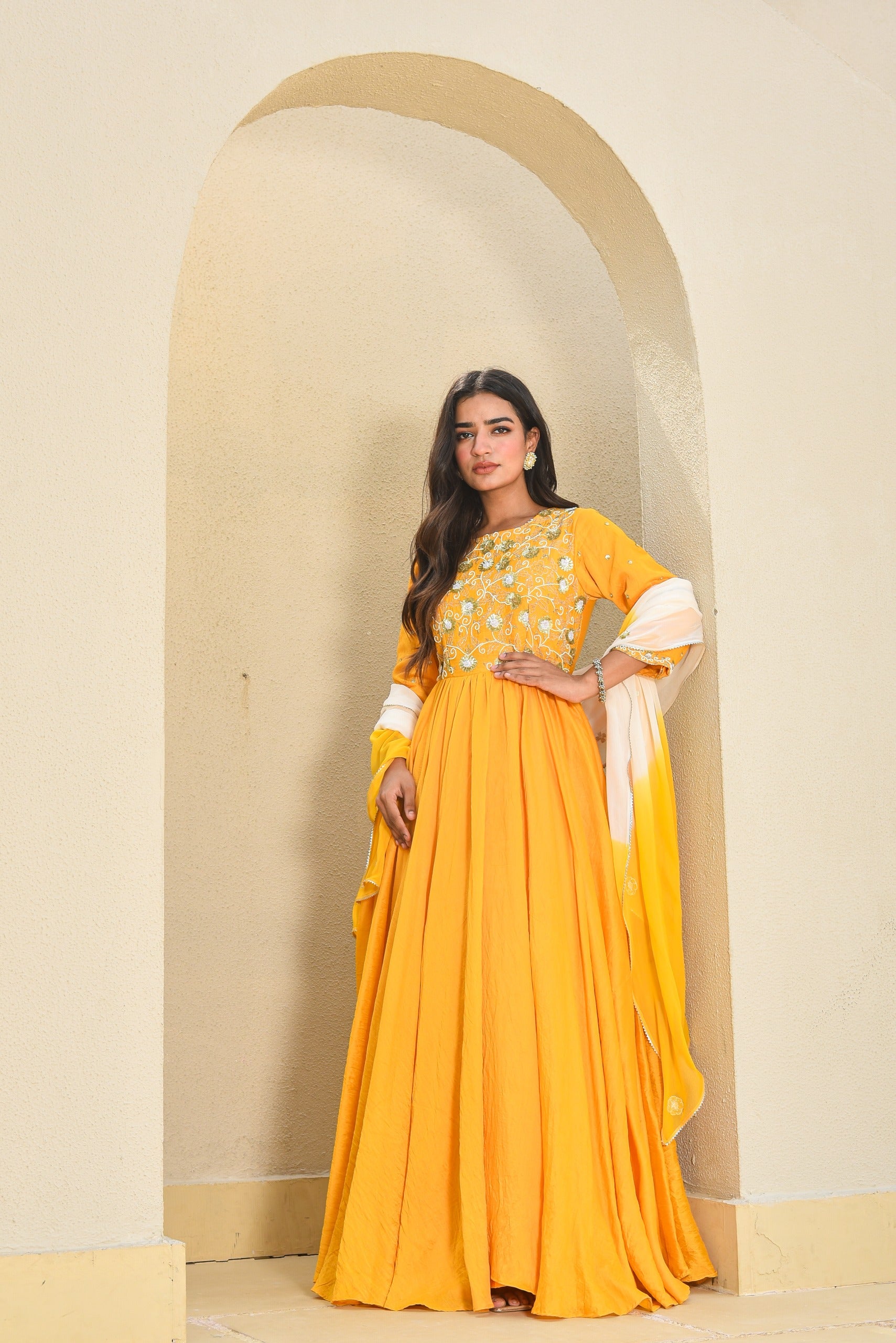 Woman in a yellow traditional outfit standing in front of an archway.