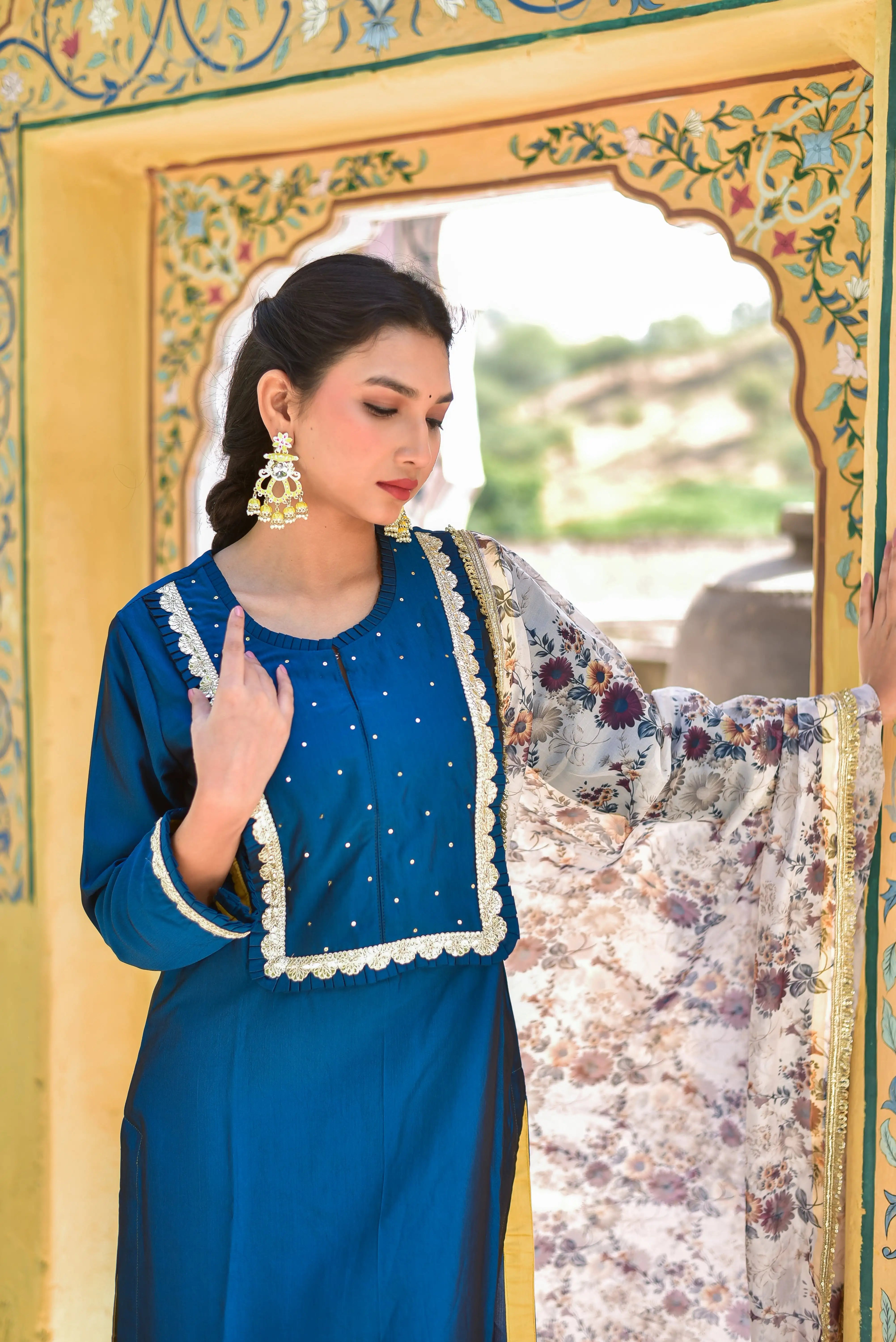 The Peacock Blue Kurta & Pant Set is a stunning ensemble that exudes elegance and sophistication. The rich peacock blue hue is complemented by intricate floral patterns on the dupatta, adding a touch of artistic flair to the overall design. The kurta features a classic round neckline and long sleeves, while the matching pants provide a comfortable and stylish bottom half. The floral dupatta adds a pop of color and texture, making this set perfect for any special occasion or formal event.