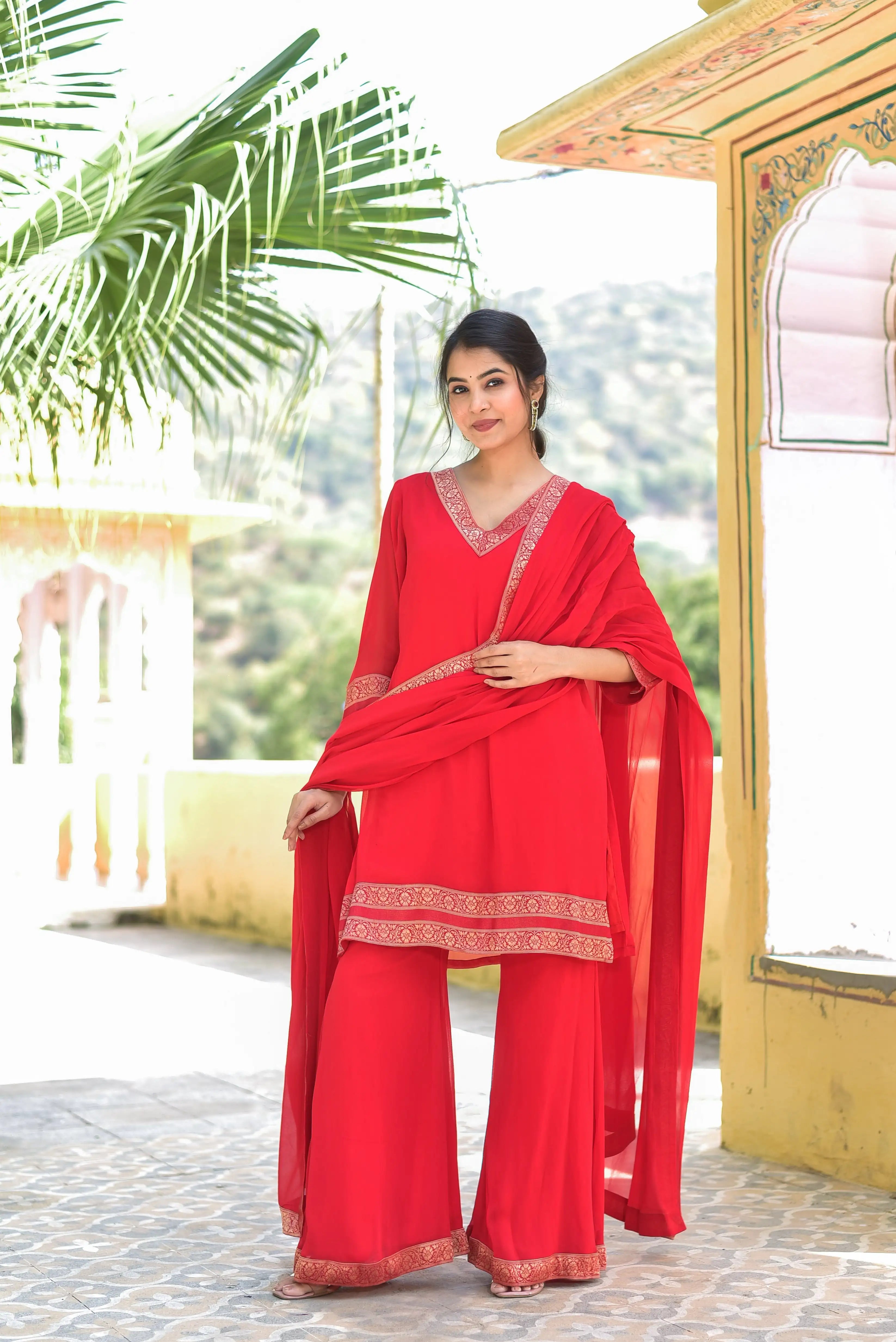 The Classic Red Brocade Kurta Set is a stunning ensemble that embodies timeless elegance and traditional craftsmanship. The vibrant red hue, reminiscent of auspiciousness and joy, is beautifully complemented by intricate brocade detailing that adds a touch of royal grandeur to the overall design. The kurta's V-neckline and 3/4 sleeves create a flattering silhouette, while the straight-cut palazzo pants with a matching border at the bottom provide a comfortable and stylish fit.