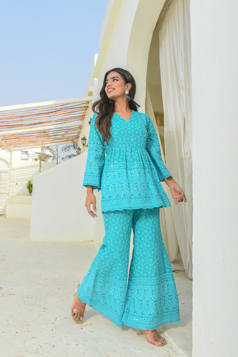 Woman in a turquoise outfit standing in a bright outdoor setting