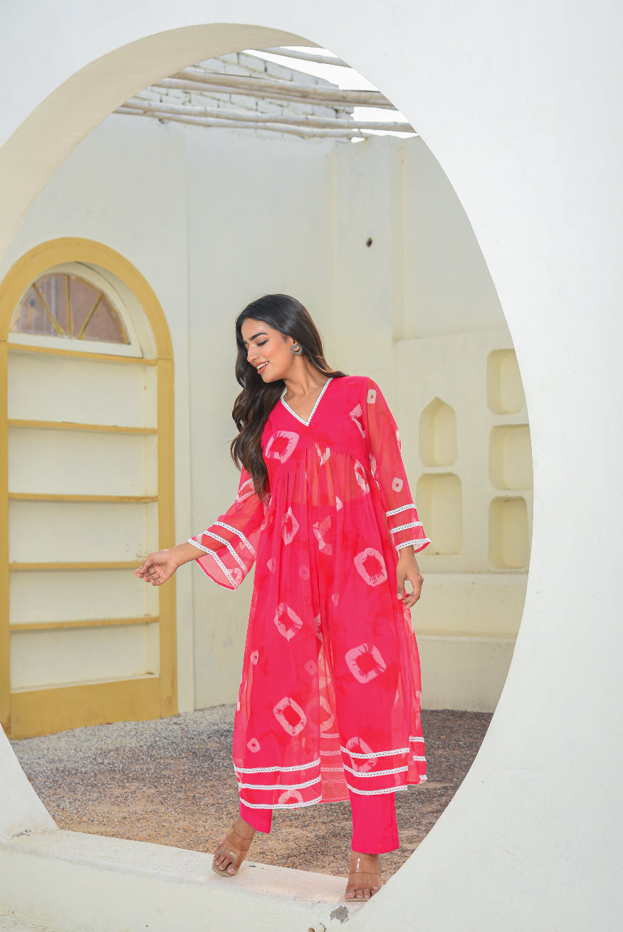 Woman in a pink outfit standing in a decorative room with arches and shelves.