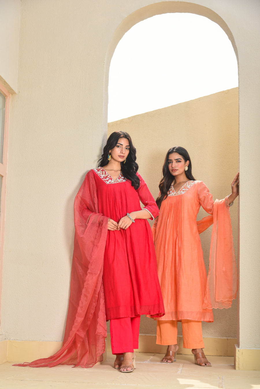 Two women in matching traditional outfits standing in a doorway.