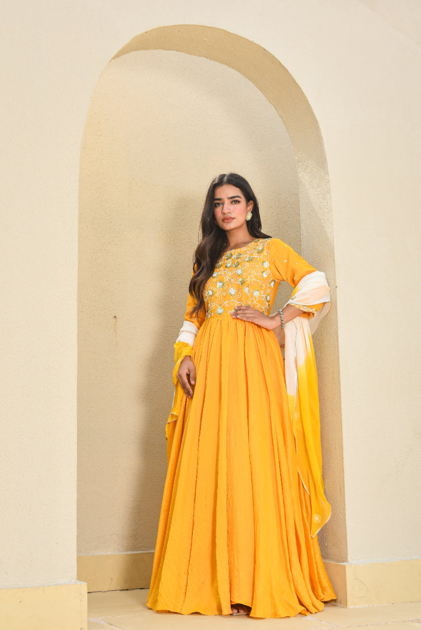 Woman in a yellow traditional outfit standing in front of an archway.