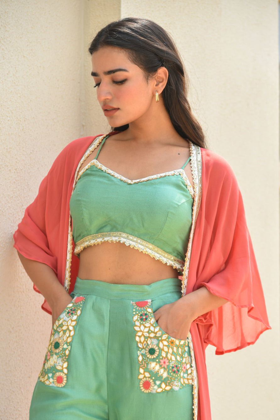 Woman wearing a green traditional outfit with a pink shawl against a neutral background