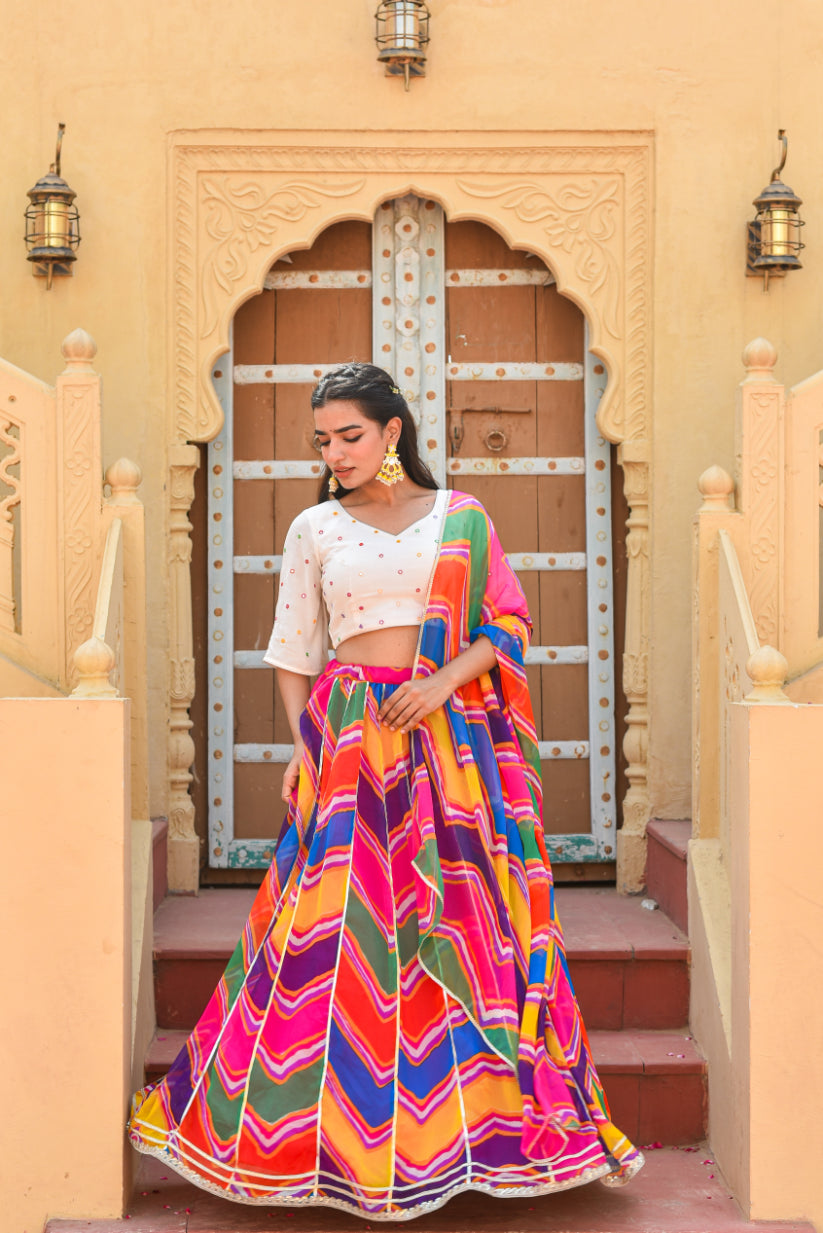 Woman in a colorful traditional outfit standing in front of an ornate door.