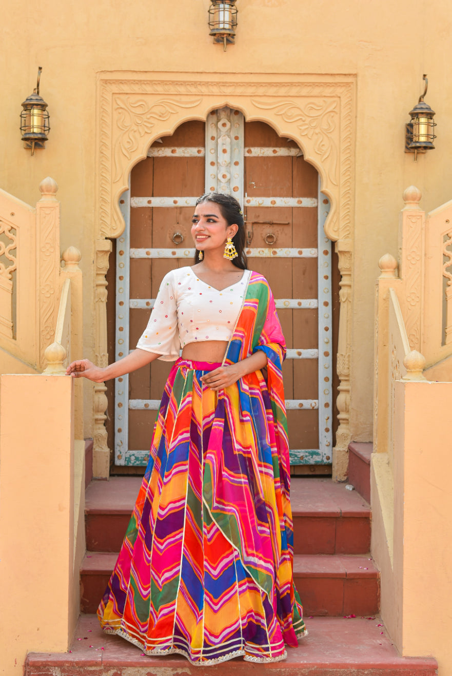 Woman in a colorful traditional outfit standing in front of a decorative door.