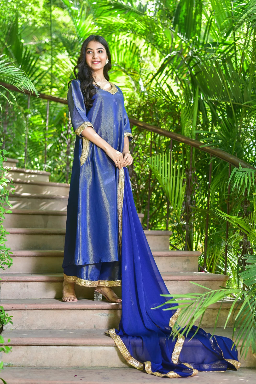 The Ocean Pearl Kurta Set is a luxurious 3-piece ensemble that captures the depth and beauty of the ocean. The set features rich zari silk fabric with exquisite gold lace work, perfect for festive celebrations and special occasions. The kurta boasts a stunning blue hue with intricate gold lace detailing, while the palazzo pants and dupatta add a touch of elegance to the overall look. With its timeless design and high-quality materials, this set is sure to make a statement at any event.
