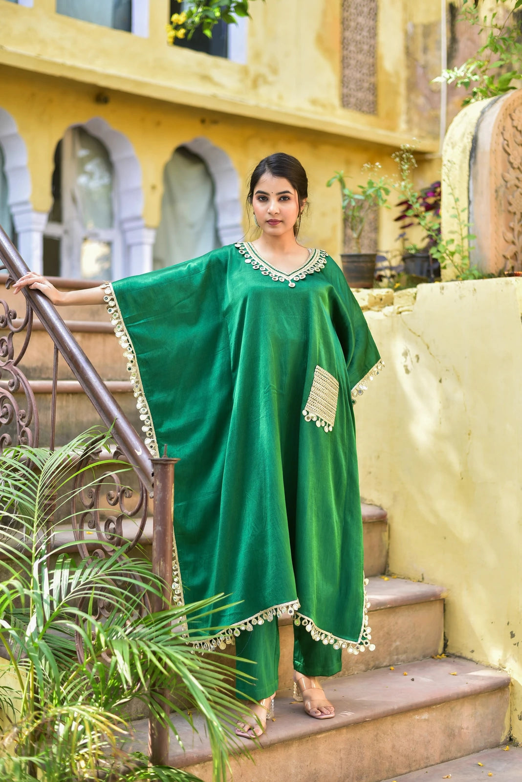 The Forest Glaze Mirror Work Set is a stunning and elegant kaftan set that exudes regal sophistication. Crafted from luxurious Gazzi satin, this set features exquisite mirror work detailing that catches the eye, while the emerald green color evokes the richness of the forest. The kaftan's loose fit and V-neckline create a comfortable and stylish silhouette, perfect for making a statement at any occasion.