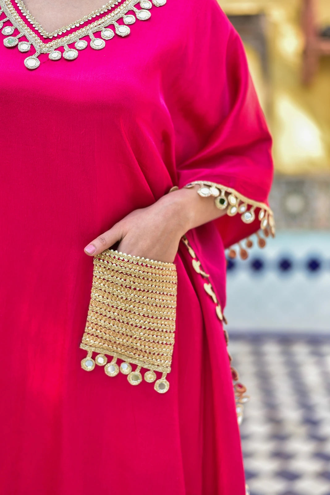 The Gulabi Glaze Mirror Work Set is a stunning ensemble crafted from luxurious Gazzi Satin fabric, exuding elegance and sophistication. The rich, deep pink hue of the set is complemented by intricate mirror work detailing that adds a touch of glamour and sophistication. The set features a kaftan-style top with a relaxed fit, perfect for making a statement at any occasion. The sleeves are adorned with delicate mirror work, adding a touch of whimsy and playfulness to the overall design.