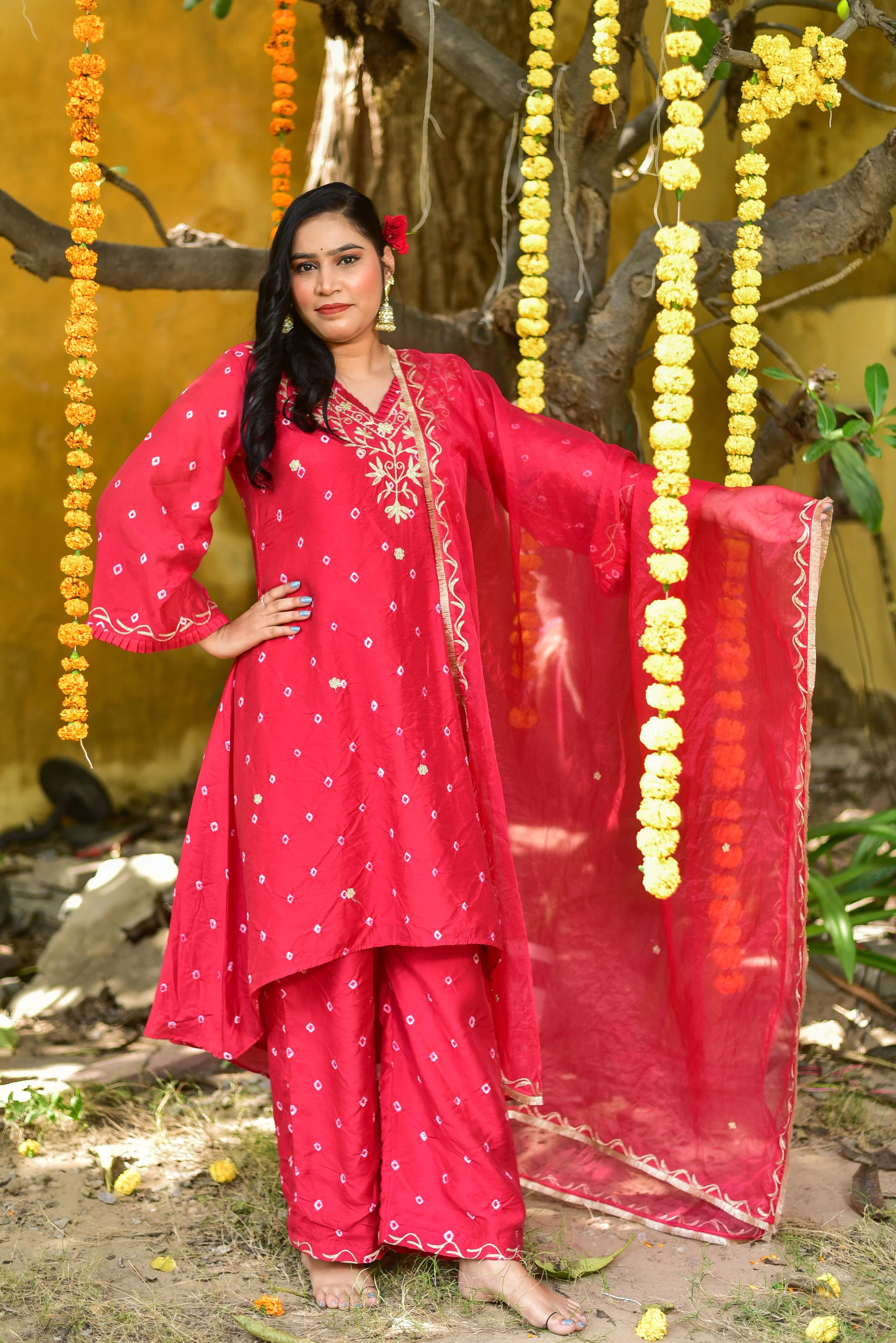 The red Bandhej asymmetrical kurta set is a stunning piece of clothing that showcases traditional craftsmanship with a modern twist. The asymmetrical design adds a touch of contemporary elegance to the classic Bandhej pattern, creating a unique and eye-catching look.

The kurta features intricate tie-dye artistry, with a vibrant red hue that is both bold and sophisticated. The fabric appears to be of high quality, with a smooth texture that drapes elegantly on the body.