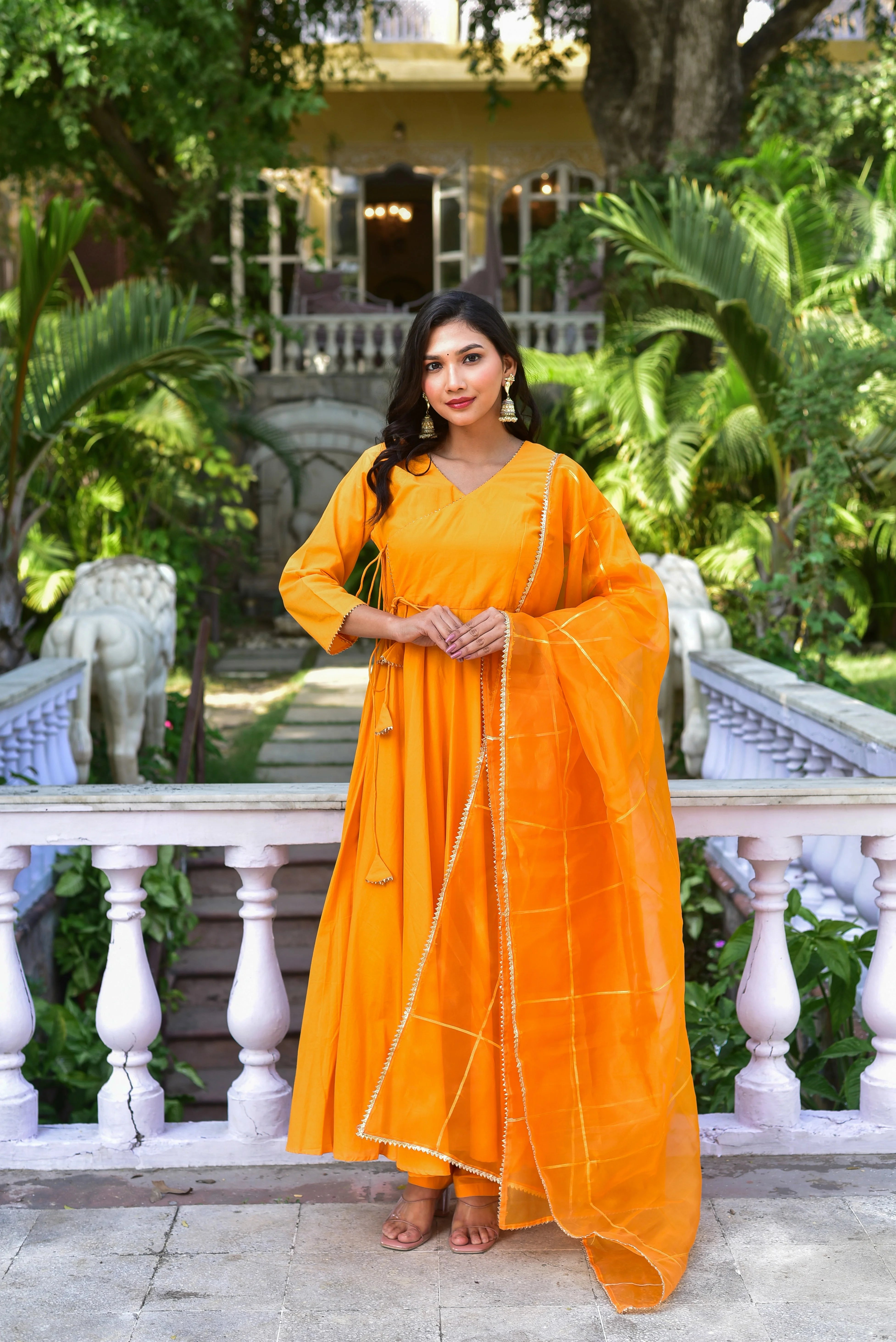 The image showcases a stunning Haldi Yellow Angrakha Anarkali Set, a perfect blend of traditional craftsmanship and contemporary elegance. This vibrant ensemble features a luxurious fabric, intricate detailing, and a classic V-neckline, making it a must-have for any fashion-forward individual looking to make a statement at their next special occasion. With its comfortable fit and timeless design, this set is sure to turn heads and leave a lasting impression.