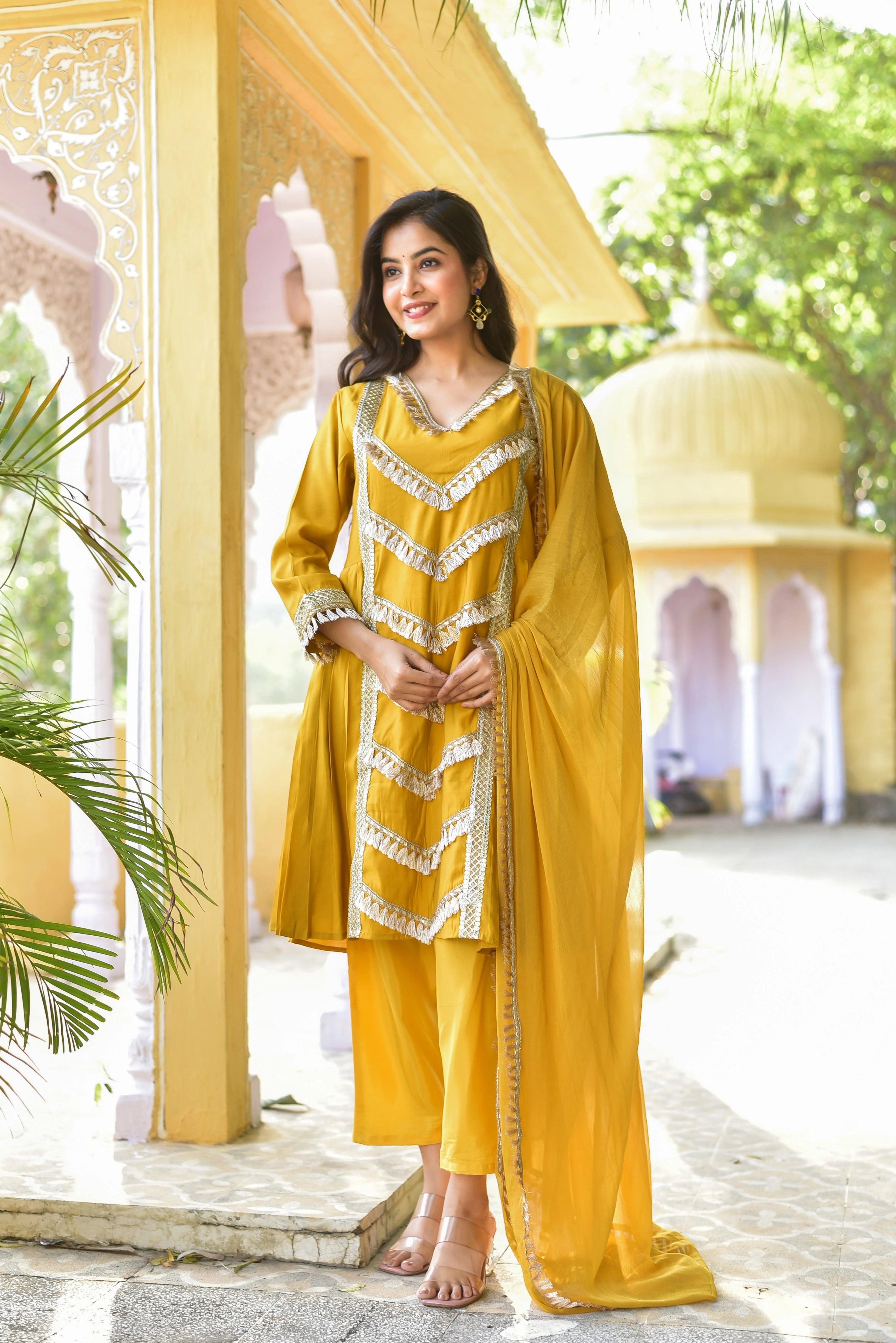 This yellow gold kurta and pant set is a stunning example of traditional Indian elegance, perfect for special occasions and celebrations. The vibrant yellow hue exudes warmth and joy, while the intricate gold accents add a touch of sophistication and luxury. The kurta's V-neck design and 3/4 sleeves create a flattering silhouette, and the matching pants provide a seamless and elegant look. The set's fabric appears to be a luxurious silk or satin, ensuring a smooth and comfortable fit.