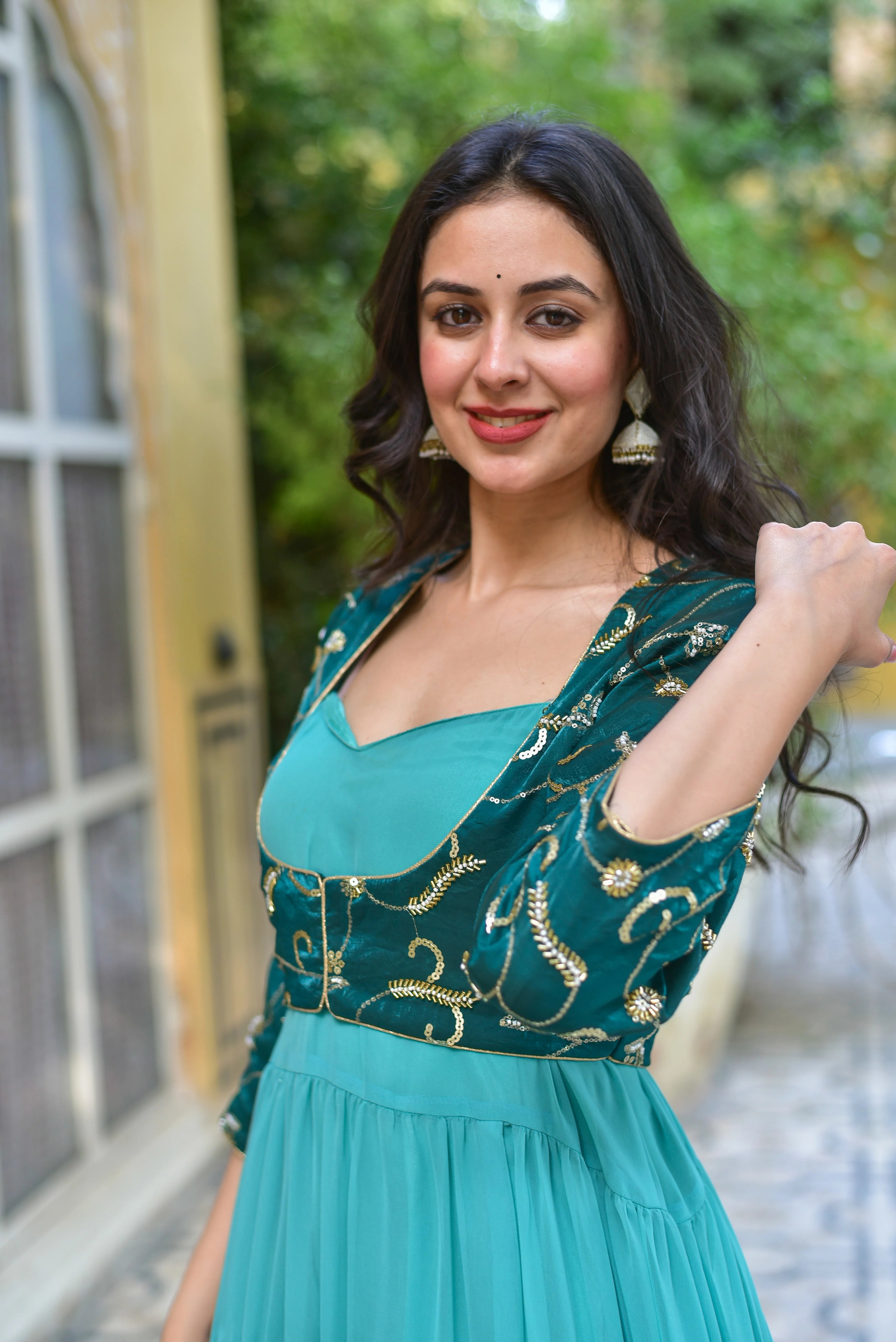 The image showcases a woman wearing a stunning green dress with a matching jacket, exuding elegance and sophistication. The dress features a flowing georgette fabric with a tiered design, creating a beautiful and feminine silhouette. The jacket is made of velvet and boasts intricate embroidery, adding a touch of luxury and refinement to the overall look.

This ensemble is perfect for making a statement at any special occasion, whether it's a wedding, a formal gala, or a night out with friends.