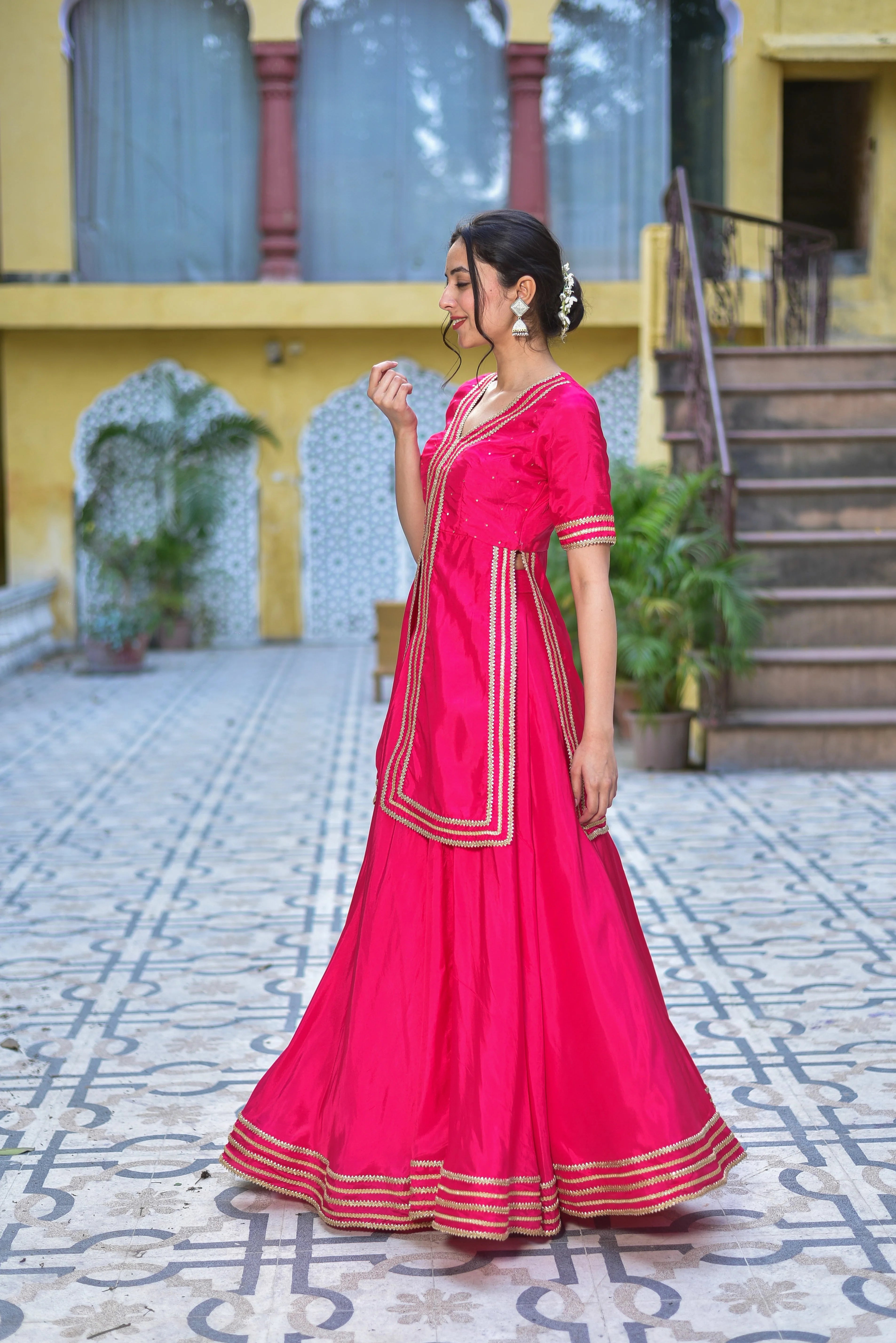 The Pink Rani sa indo-western set is a stunning fusion of traditional elegance and contemporary fashion, crafted from luxurious silk blend fabric that drapes beautifully and feels incredibly soft against your skin. This elegant ensemble features intricate gold accents that add a touch of sophistication, making it perfect for special occasions or formal events. With its unique blend of traditional and modern elements, this set is sure to make a statement and elevate your style to the next level.