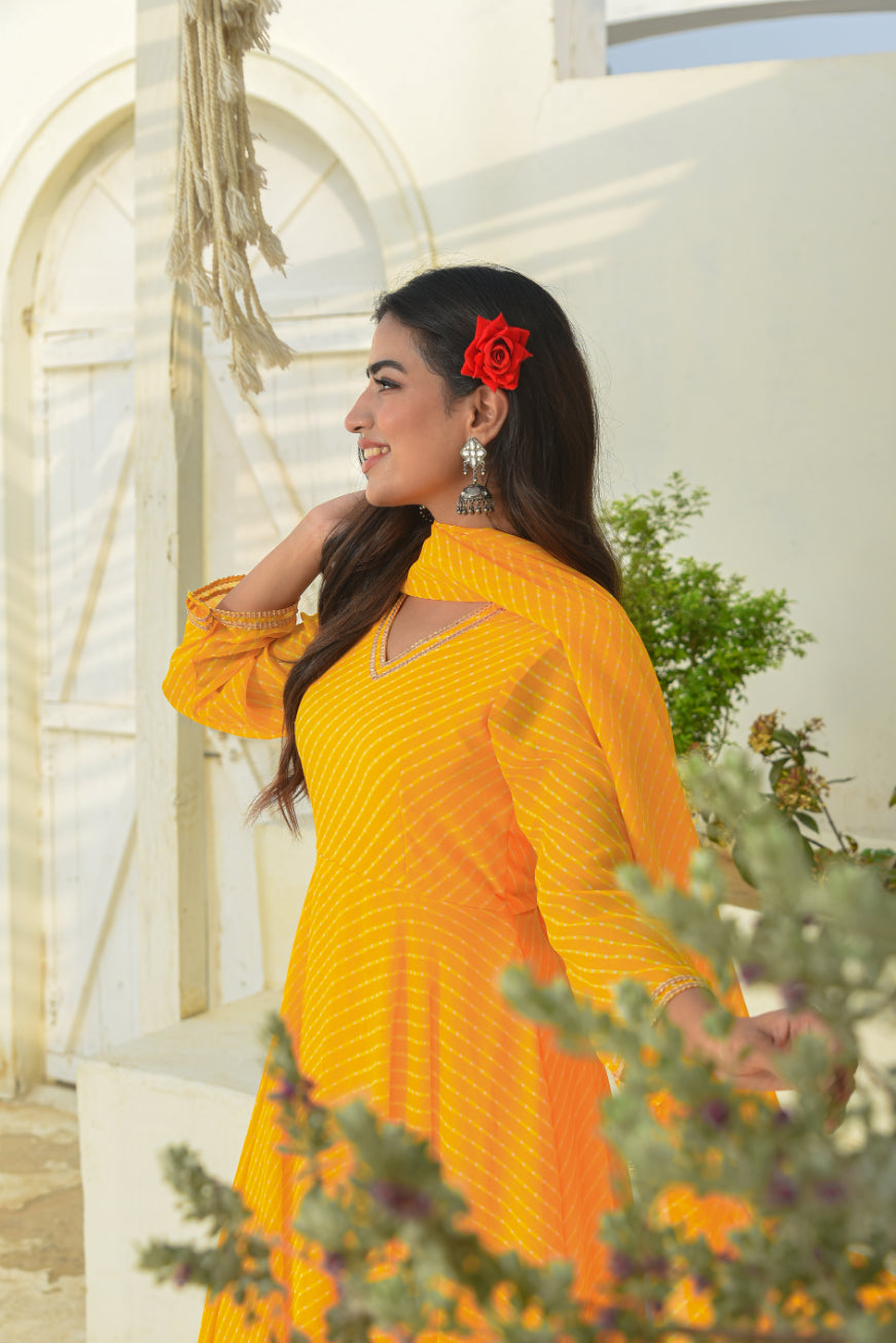Woman in a bright yellow dress with a red flower in her hair, standing outdoors.