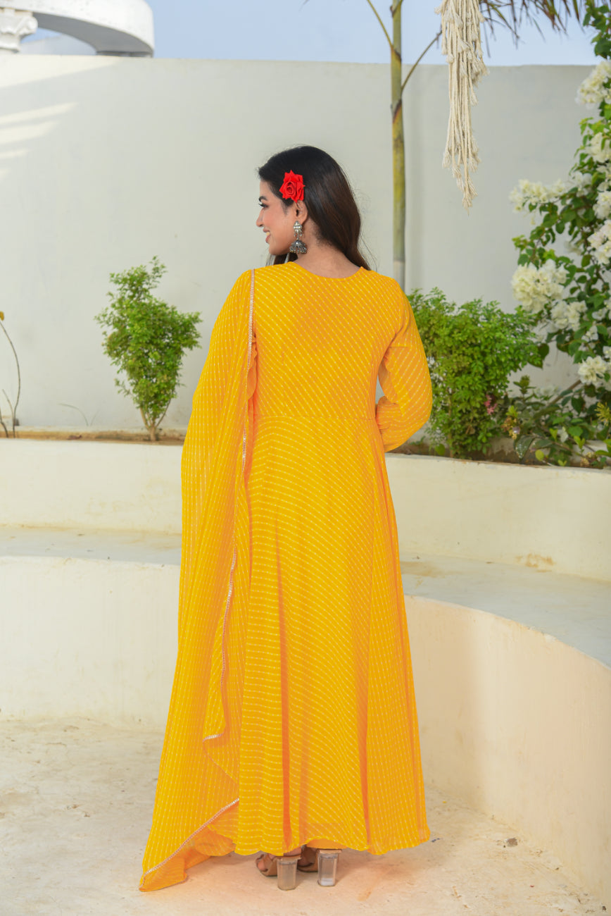 Woman in a yellow dress standing outdoors with greenery in the background