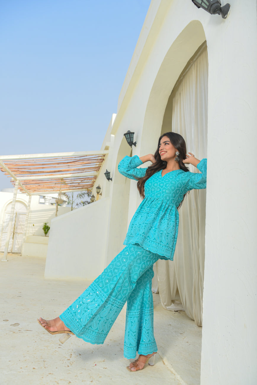Woman in a turquoise outfit standing against a white architectural background