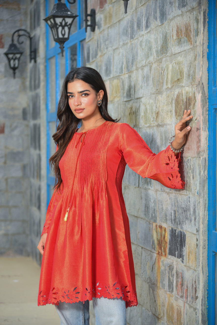 Woman wearing a red dress standing against a stone wall.