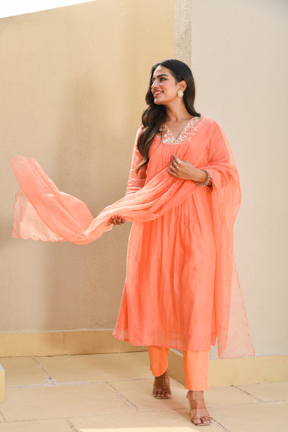 Woman in a peach traditional outfit with a beige background