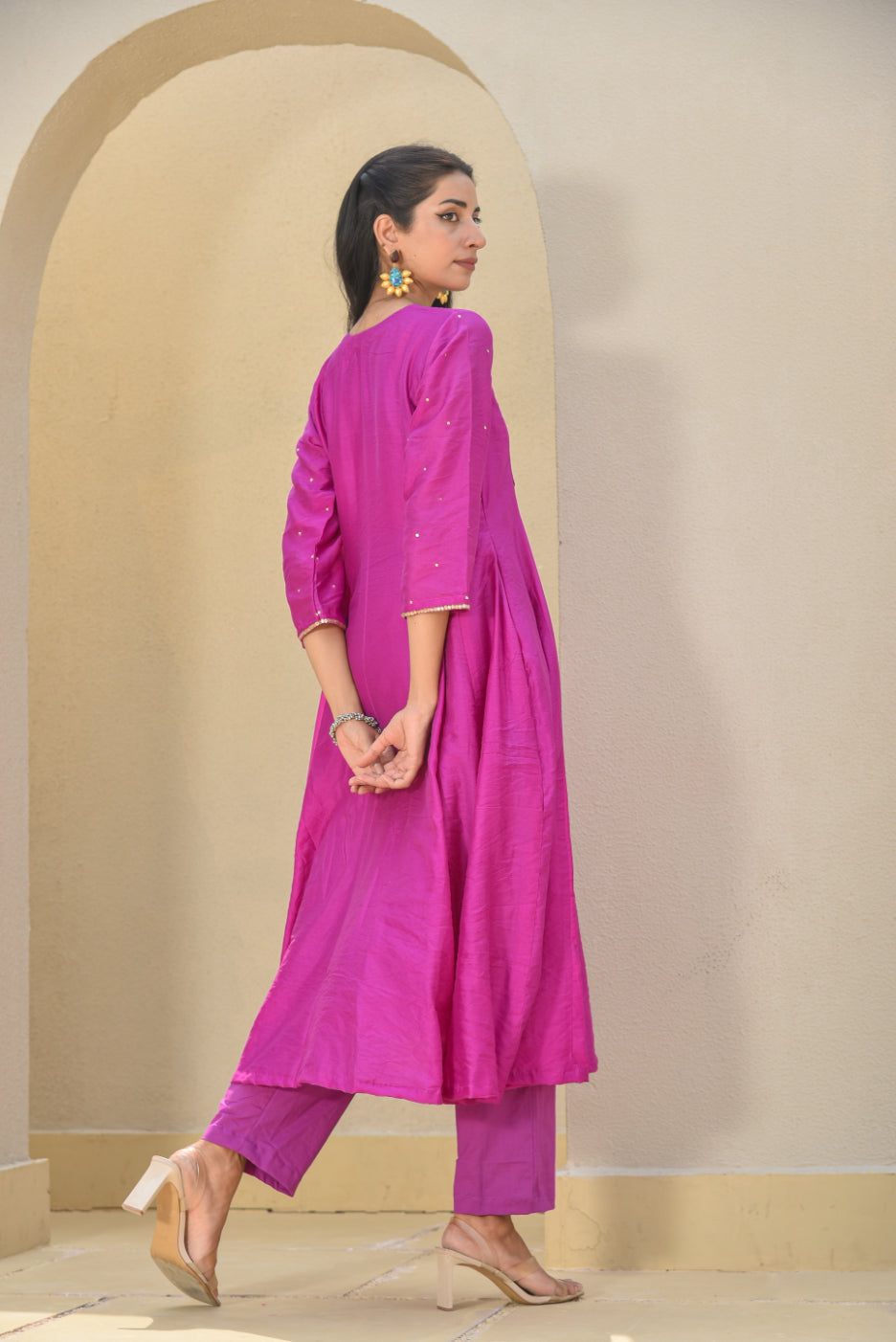 Woman wearing a bright pink traditional outfit with a beige background