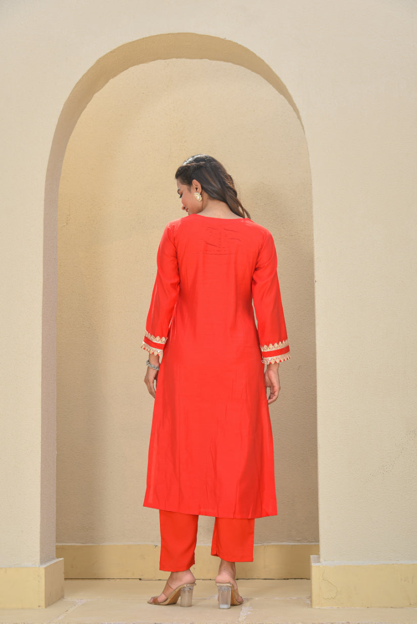 Woman wearing a red kurta with white trim in an archway.