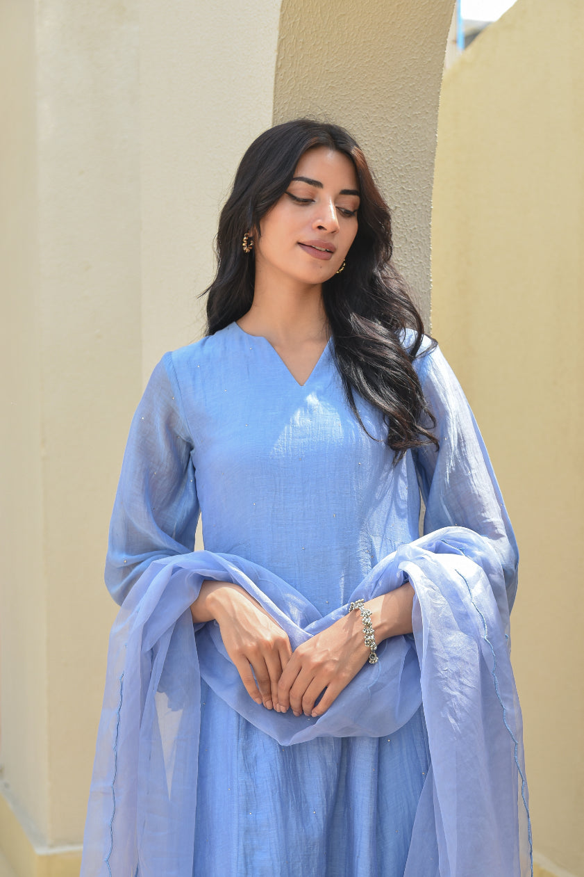 Woman wearing a light blue traditional outfit with a plain background