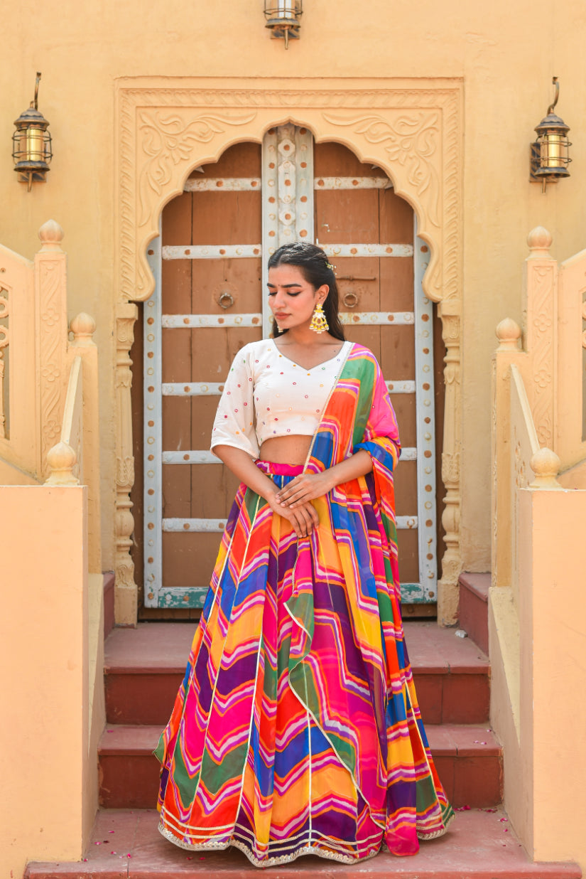 Woman in a colorful traditional outfit standing in front of an ornate door.