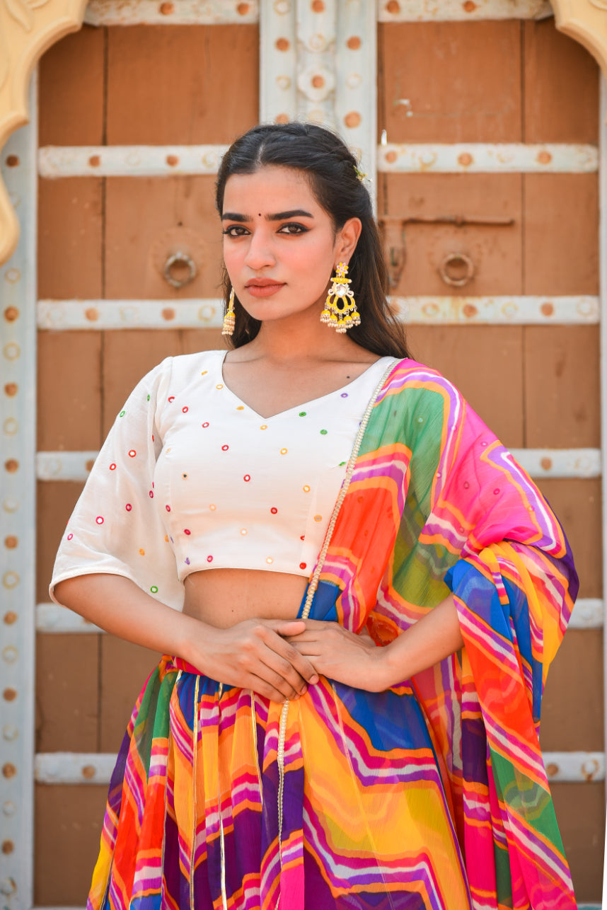 Woman wearing a colorful saree in front of a decorative wooden door.