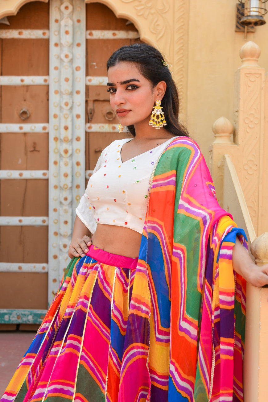 Woman in a colorful traditional outfit standing against an ornate architectural background
