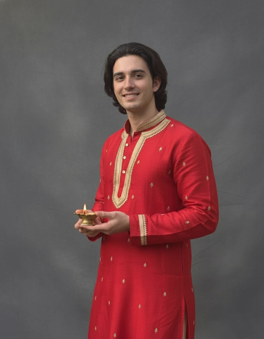 Man in a red traditional outfit holding a small object against a gray background