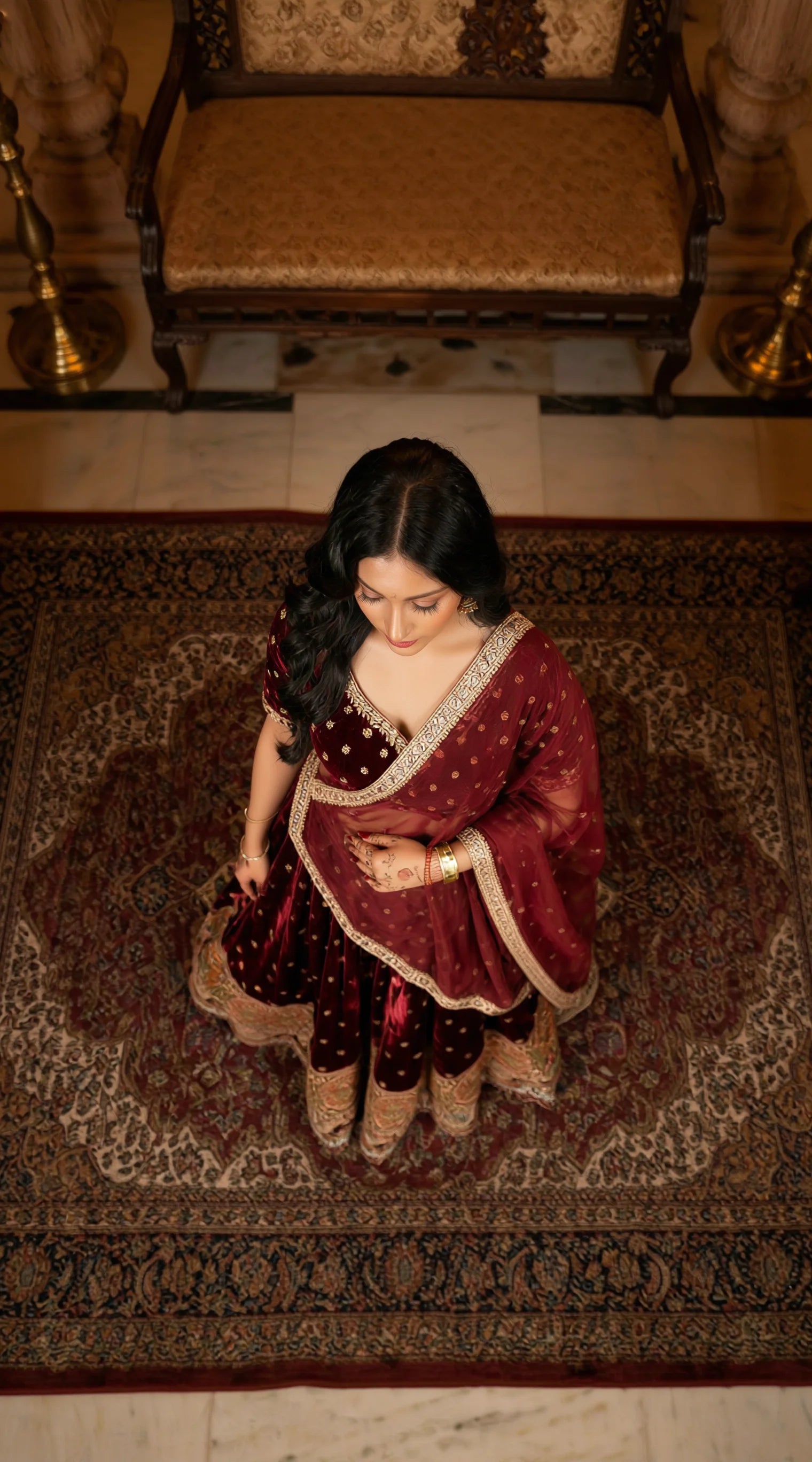 Luxury women's velvet lehenga outfit in deep maroon with statement gold embellishments.