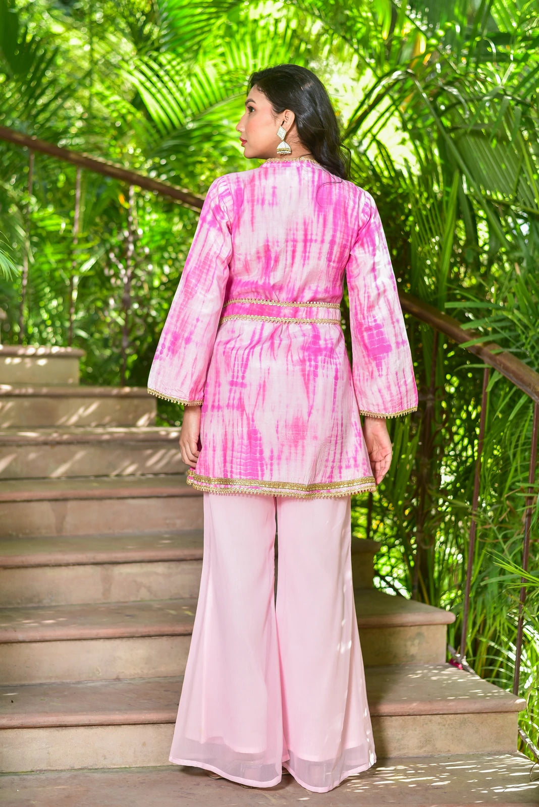 The Roseberry Pink Shibori Co-ord Set is a stunning 3-piece ensemble that showcases the beauty of hand tie-dye shibori patterns. This elegant set features a contemporary silhouette and traditional artisan techniques, making it perfect for festive occasions. The set includes a pink shibori top with a mandarin collar, long sleeves, and a tie-dye pattern, paired with matching pants and a dupatta.