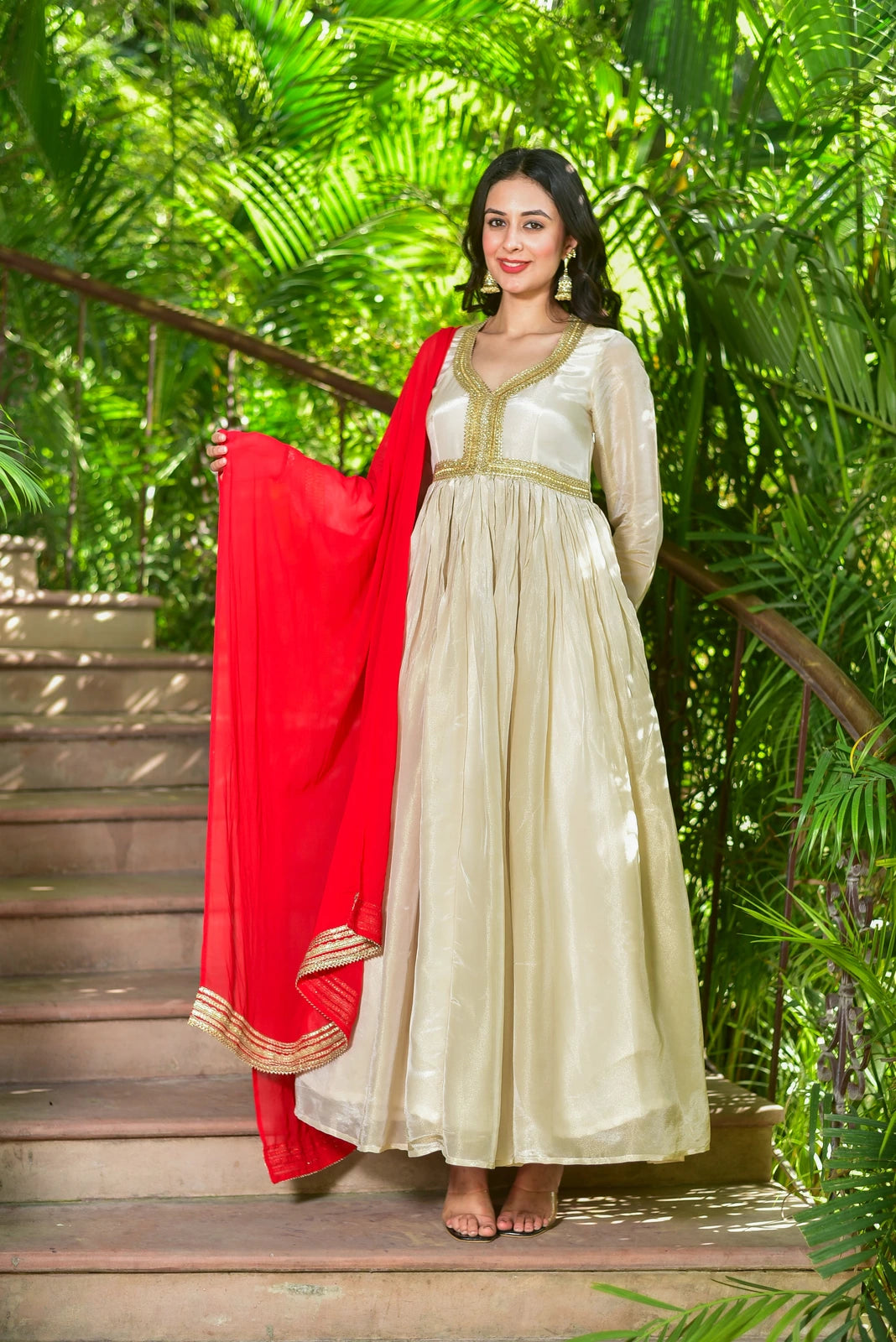 The Shahi Silk Anarkali Set is a stunning 2-piece ensemble that embodies timeless grace and festive grandeur. The cream zari silk anarkali dress features exquisite gold lace detailing, while the red dupatta adds a pop of color to complete the look. This luxurious set is perfect for any occasion, from formal events to festive celebrations, and is sure to make you feel like royalty.