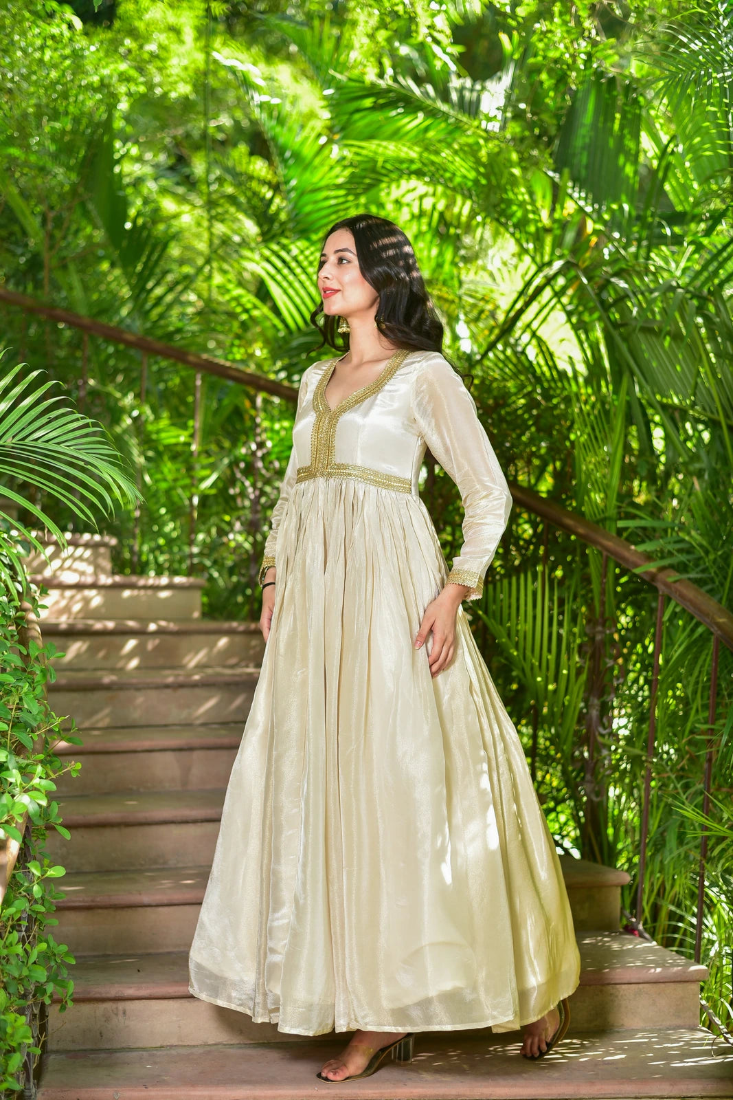 The Shahi Silk Anarkali Set is a luxurious 2-piece ensemble that embodies timeless elegance and festive grandeur. This stunning set features a flowing anarkali dress in rich cream zari silk with exquisite gold lace detailing, paired with a matching dupatta. The dress boasts a classic V-neckline and long sleeves, exuding sophistication and poise. The intricate gold lace work adds a touch of opulence, making this set perfect for special occasions and celebrations.