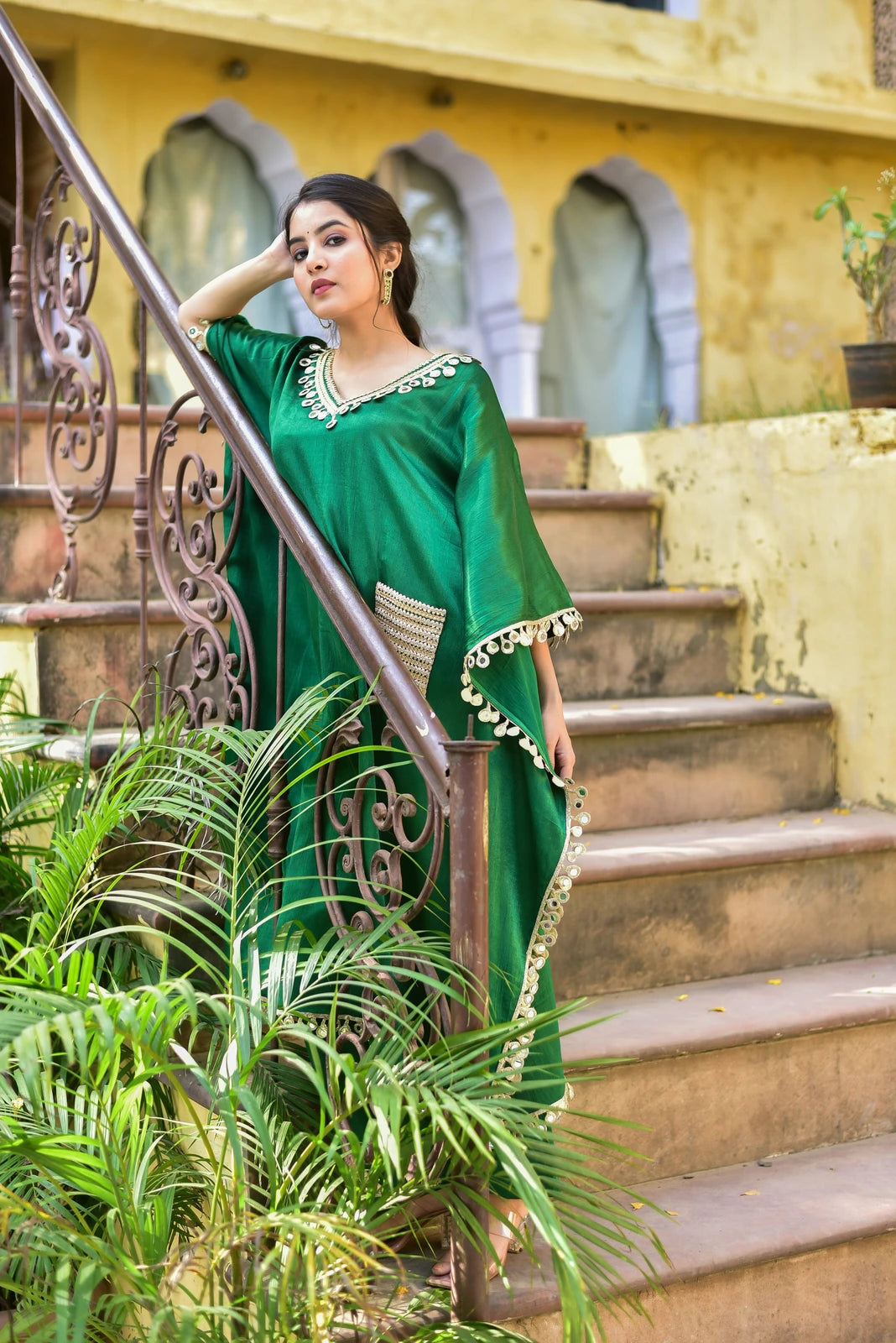 The Forest Glaze Mirror Work Set is a stunning ensemble that exudes elegance and sophistication. Crafted from luxurious Gazzi Satin, this kaftan set features intricate mirror work detailing that adds a touch of glamour to any occasion. The emerald green color is both rich and vibrant, evoking the lush forests of the natural world. The kaftan's flowy design and V-neckline create a flattering silhouette, while the mirror work accents add a subtle shine that catches the light.