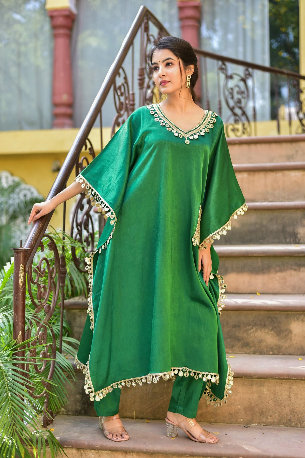 Elegant and Trendy Kaftan Set

The Chili Glaze Mirror Work Set is a stunning ensemble that exudes elegance and sophistication. Crafted from luxurious Gazzi Satin, this set features a rich emerald green color that is both timeless and versatile. The kaftan-style top boasts a loose, flowing design that drapes elegantly on the body, while the matching pants provide a comfortable and streamlined silhouette.

The set is adorned with intricate mirror work detailing that adds a touch of glamour and sophistication.