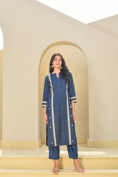 This navy blue set features a kurta with a slit neckline and 3/4 sleeves, crafted from rich Pollyn silk with elegant zari work. Paired with a comfortable cotton pant featuring a half-elastic waist and pull-up kurta closure, it offers a perfect blend of style and comfort for festive or semi-formal occasions.
